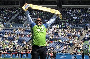 SHA Executive Andrew Lofton holds up Golden Scarf presented by Seattle Sounders FC