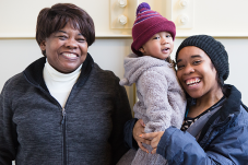 Two smiling women and a toddler standing together