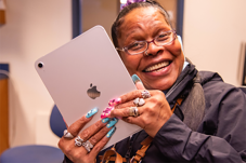Smiling woman holds up iPad