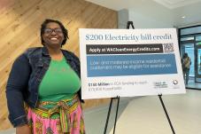 woman stands by sign about Clean Energy Credit
