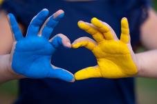 Hands forming a heart shape in blue and yellow, colors of Ukraine