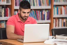 Young man at laptop in library