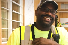 A man smiling and wearing construction work clothes