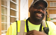 A man smiling and wearing construction work clothes