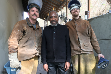 Man standing between two men in wearing protective gear for welding