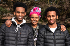Woman standing with two teenage boy high school graduates