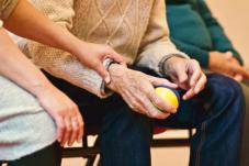 Hands of younger person holding hand of elderly person