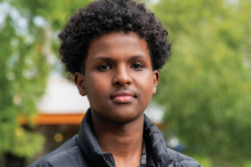 Portrait of teenage boy with foilage in background