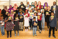Group of adults and children holding up Somali alphabet book