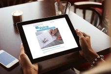 Woman's hands holding iPad with The Voice newsletter displayed on it