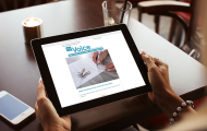Woman's hands holding iPad with The Voice newsletter displayed on it
