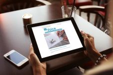 Woman's hands holding iPad with The Voice newsletter displaying on it