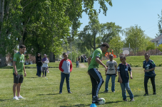 Adult soccer player demonstrates for kids standing and listening on field