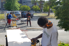 Teens work with tools preparing board and other materials for tech lab at Rainier Vista