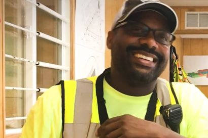 A man smiling and wearing construction work clothes