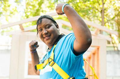 Young woman in construction gear raises her arms in triumphant gesture