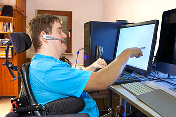 Man in a wheelchair using assisted technology on a computer screen