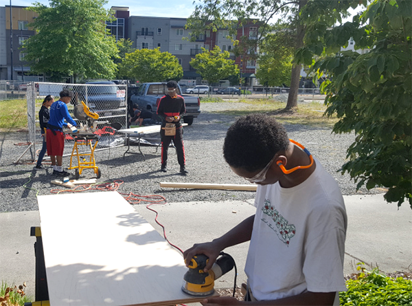 Teens work with tools to prepare board and other materials
