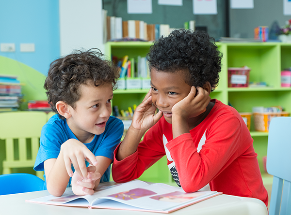 Two small boys seated around table and talking