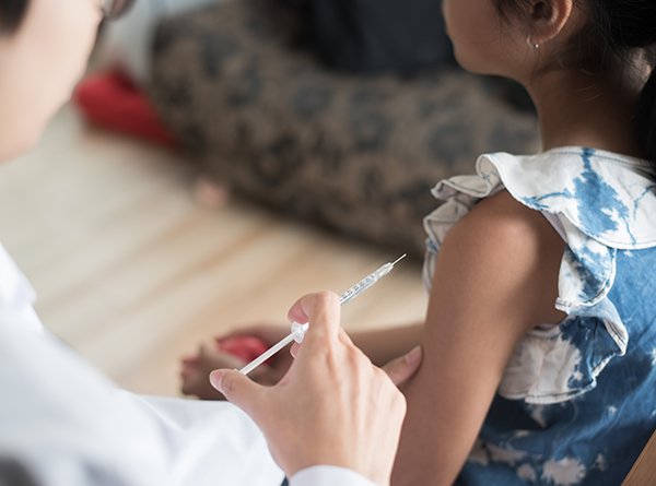 Small girl receiving injection in her arm